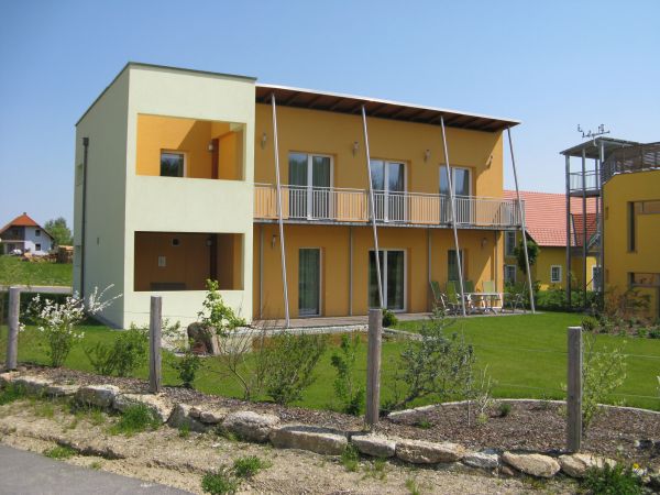 Orangenes, kubisches Passivhaus mit Garten und Balkonen