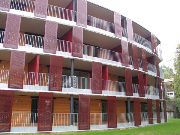 Elliptischer Holzbau mit durchgängigen Balkonen in jedem der 4 Stockwerke