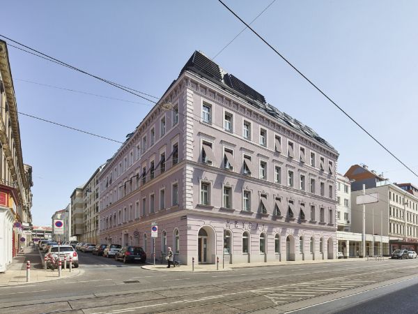 Straßenansicht mit der restaurierten Fassade (mit hochwärmedämmenden Aerogelputz in der Seitenstraße) und dem neuen Dachgeschoss.