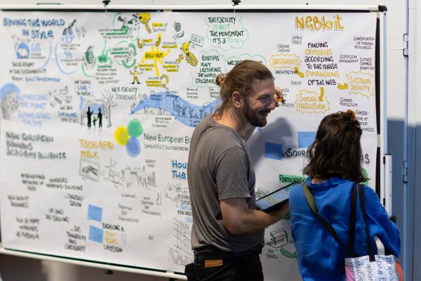 Two people talking in front of Graphic Recording