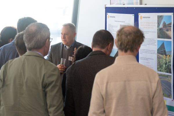 Personen stehen um eine Pinwand, auf der sich ein Poster befindet