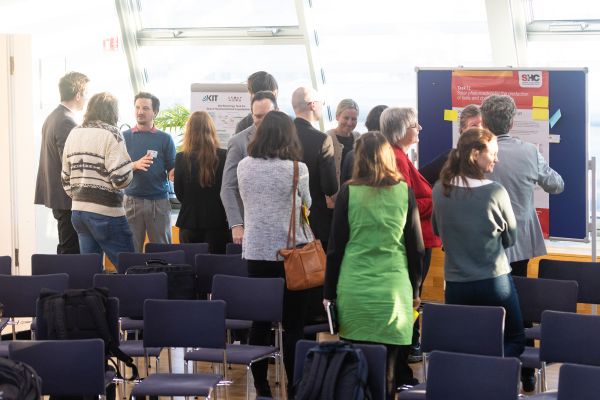 Personen stehen um Pinwände, auf denen sich Poster befinden und netzwerken