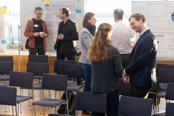 Personen stehen um Pinwände, auf denen sich Poster befinden und netzwerken