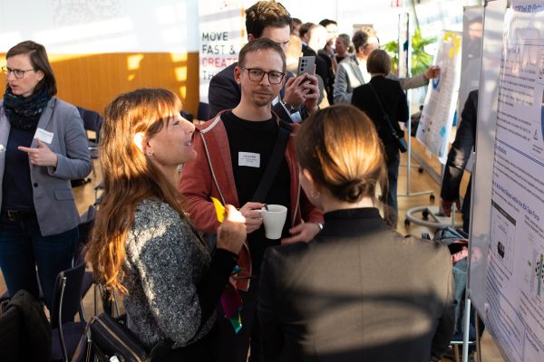 Personen stehen um Pinwände, auf denen sich Poster befinden und netzwerken