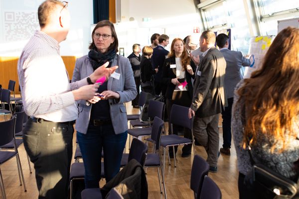 Personen stehen um Pinwände, auf denen sich Poster befinden und netzwerken