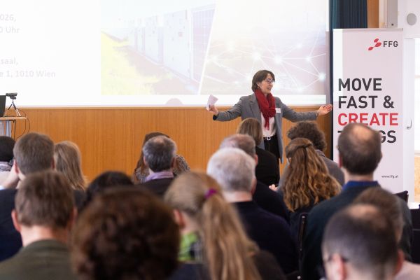 Moderatorin spricht vor Publikum im Saal