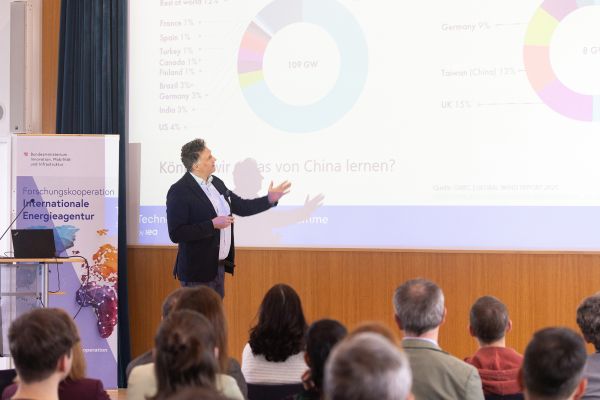 Vortragender auf dem Podium vor Publikum im Saal