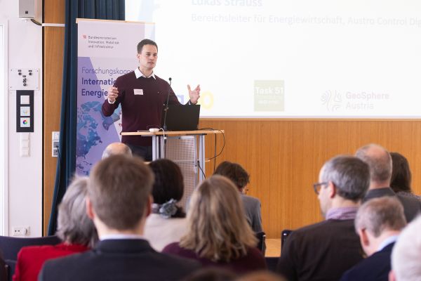 Vortragender auf dem Podium vor Publikum im Saal