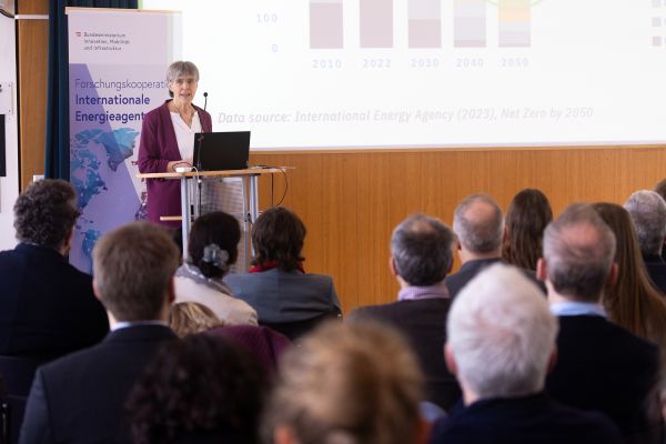 Vortragende auf dem Podium vor Publikum im Saal