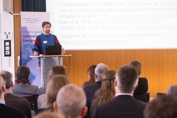 Vortragender auf dem Podium vor Publikum im Saal