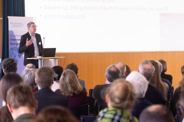 Vortragender auf dem Podium vor Publikum im Saal