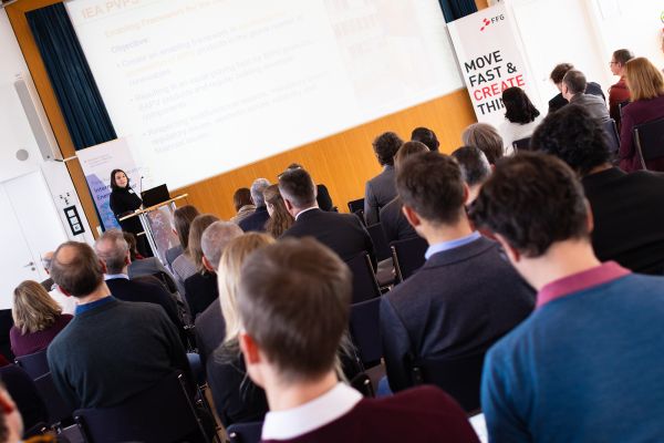 Vortragende auf dem Podium vor Publikum im Saal