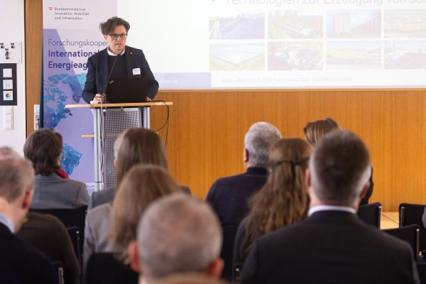 Vortragender auf dem Podium vor Publikum im Saal