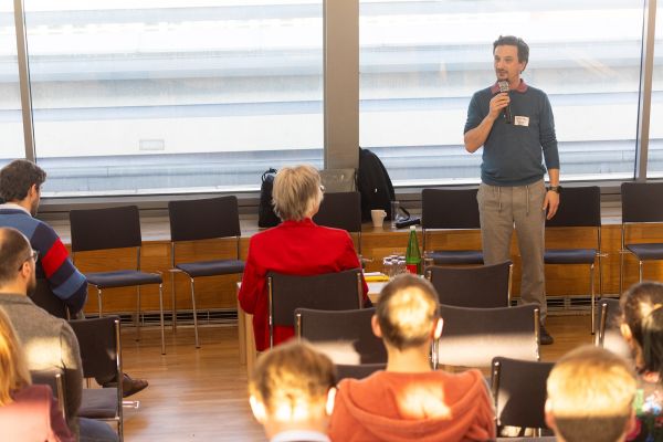 Vortragender steht vor Publikum und spricht in ein Mikrofon