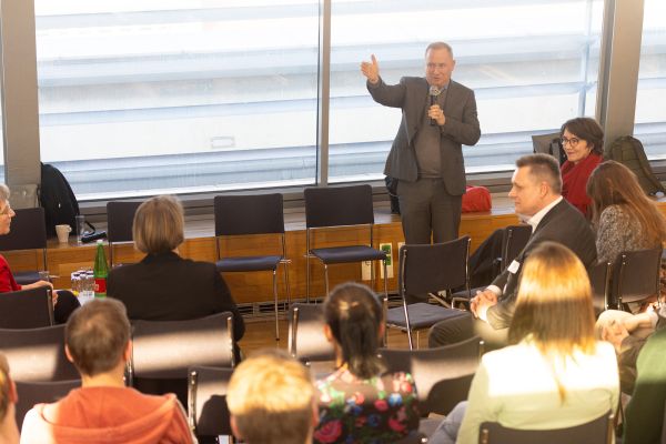 Vortragender steht vor Publikum und spricht in ein Mikrofon