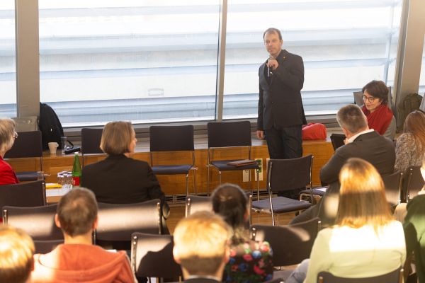 Vortragender steht vor Publikum und spricht in ein Mikrofon